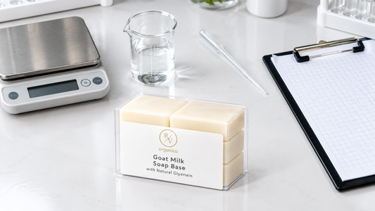 RV Organica Goat Milk Soap Base on a white lab bench beside a digital scale, glass beaker, pipette and a grid-paper clipboard