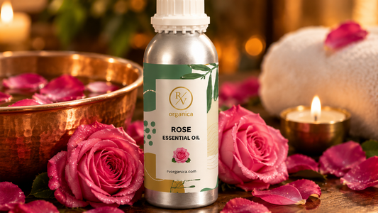 RV Organica rose essential oil beside a copper bowl of rose petal water, a rolled towel and lit candles in a spa setting