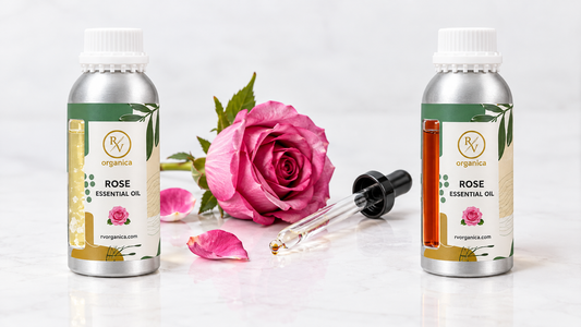 Two bottles side by side showing pale, crystallising rose otto and deep reddish rose absolute, with a fresh pink rose and a glass dropper on white marble