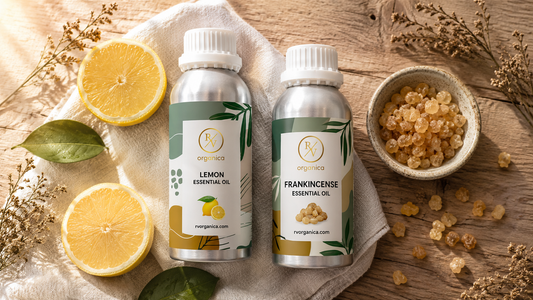 Flat lay product photography of RV Organica Lemon Essential Oil and Frankincense Essential Oil aluminum bottles on a rustic wooden surface with fresh lemon halves, Boswellia frankincense resin, dried herbs, and white linen cloth in warm natural light.