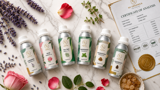 Premium RV Organica essential oil collection featuring lavender, rose, tea tree, peppermint, frankincense, and cedarwood essential oils in aluminum bottles arranged on a white marble background with botanical flowers and Certificate of Analysis.