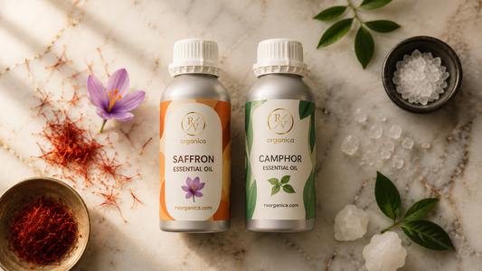 RV Organica saffron vs camphor essential oil bottles side by side on marble surface with kesar threads and camphor crystals