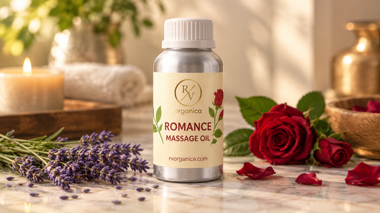 RV Organica Romance Massage Oil silver bottle on marble surface with lavender sprigs, red roses, and warm spa-inspired decor