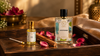 Premium RV Organica Rose Attar and Love Fusion perfume bottles arranged on a dark wooden tray with rose petals and sandalwood in warm luxury lighting.