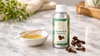 RV Organica Clove Bud Essential Oil bottle with golden oil, cotton swab, and dried cloves on a white marble surface in a premium natural skincare setting.