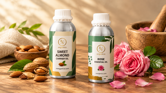 RV Organica Sweet Almond Carrier Oil and Rose Essential Oil bottles with almonds and fresh pink roses on a wooden surface