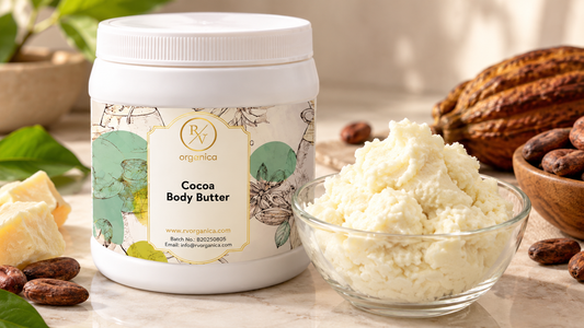 RV Organica Cocoa Body Butter jar beside a glass bowl of creamy cocoa butter, raw cocoa butter blocks, cocoa beans and a cocoa pod