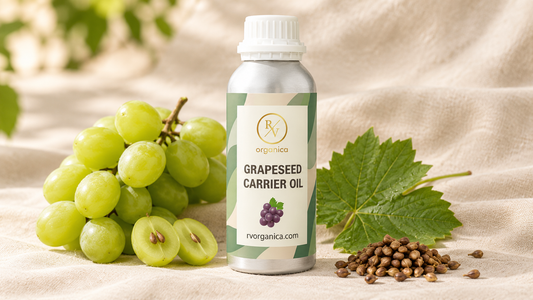 RV Organica grapeseed carrier oil bottle with fresh green grapes, halved grapes showing seeds and a pile of dried grape seeds on beige linen