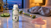RV Organica grapeseed carrier oil on a marble nightstand with a jade face roller, rose quartz gua sha, cucumber slices and a silk eye mask at dusk