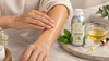 Hand massaging diluted camphor oil onto the forearm beside an RV Organica Camphor Essential Oil bottle, a bowl of carrier oil and a dropper