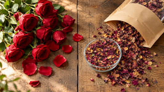 Fresh red roses beside an open pouch of shade dried rose petals on a wooden table