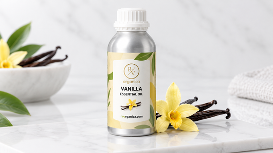 RV Organica Vanilla Essential Oil bottle on white marble with cured vanilla pods and a yellow vanilla orchid flower