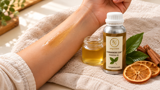 Diluted cinnamon body oil applied as a patch on the inner forearm next to a jar of carrier oil, cinnamon leaf essential oil bottle, cinnamon sticks and dried orange slices