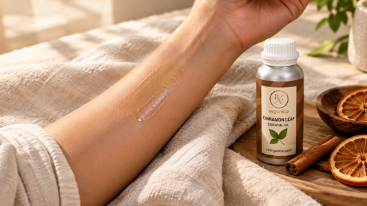 Patch test of diluted cinnamon oil on the inner forearm resting on a linen cloth, with a cinnamon leaf essential oil bottle, cinnamon sticks and dried orange slices