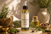 RV Organica rosemary hair oil with biotin, jojoba and castor oils surrounded by fresh rosemary sprigs and natural hair care ingredients