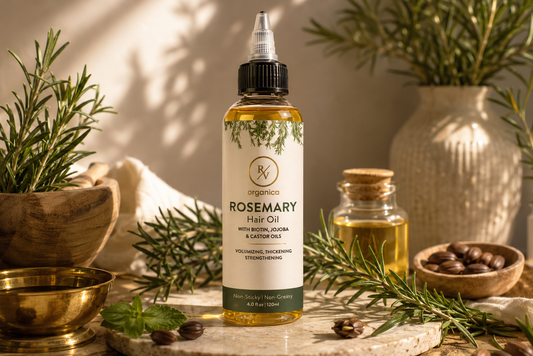 RV Organica rosemary hair oil with biotin, jojoba and castor oils surrounded by fresh rosemary sprigs and natural hair care ingredients