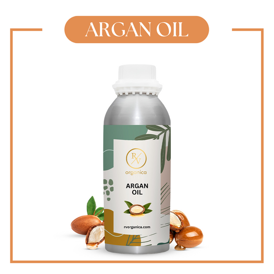 A bottle of Argan Oil with a white label, displaying the product name and the brand VedaOils, alongside argan nuts and leaves.