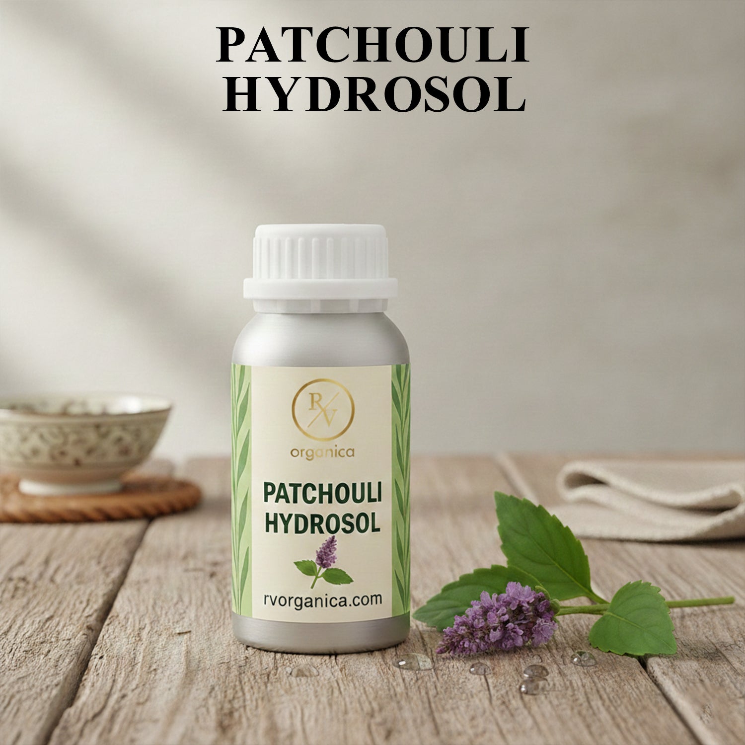 Organic Patchouli Hydrosol facial mist bottle with fresh patchouli leaves and flowers, natural aromatic skin toner for hydration and daily skincare.