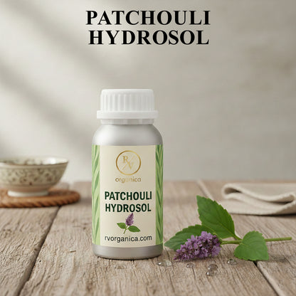 Organic Patchouli Hydrosol facial mist bottle with fresh patchouli leaves and flowers, natural aromatic skin toner for hydration and daily skincare.
